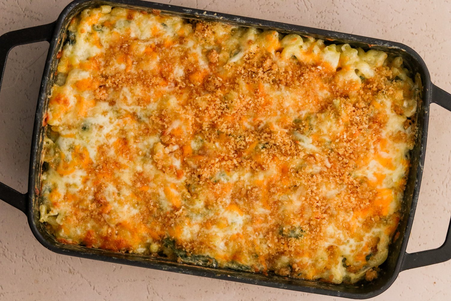 Baked spinach and artichoke mac and cheese, the top bubbling and browned.