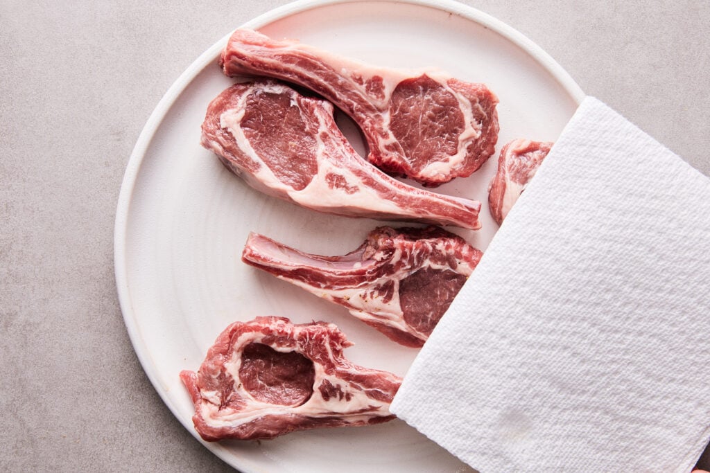 patting lamb chops dry with a paper towel