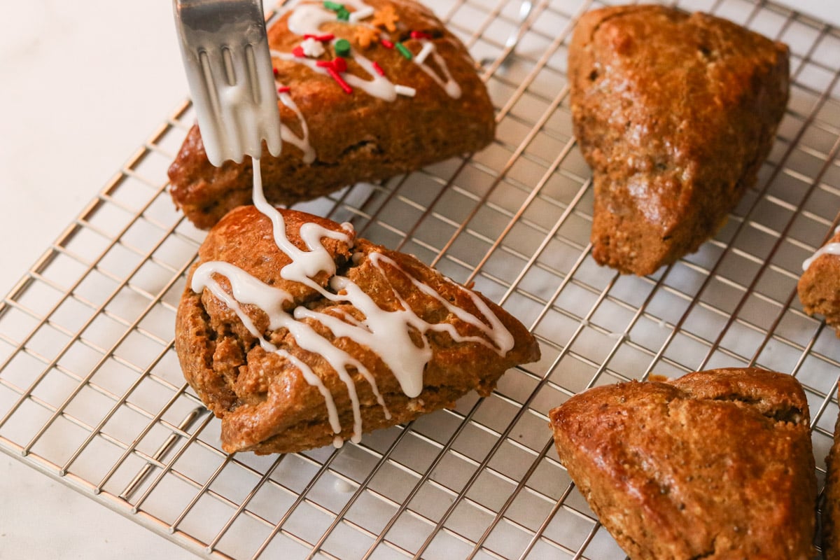 Gingerbread scones being glazed with a fork.
