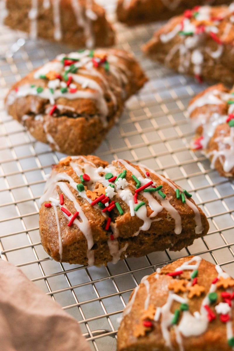 Gingerbread scones on a cooling rack with a drizzle of glaze and festive sprinkles.