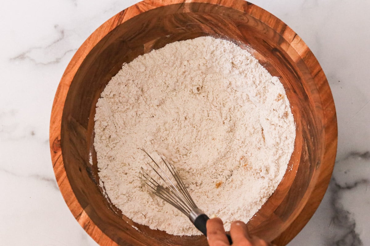 Flour, brown sugar, baking powder, salt, ginger, cinnamon, and cloves in a wooden mixing bowl.