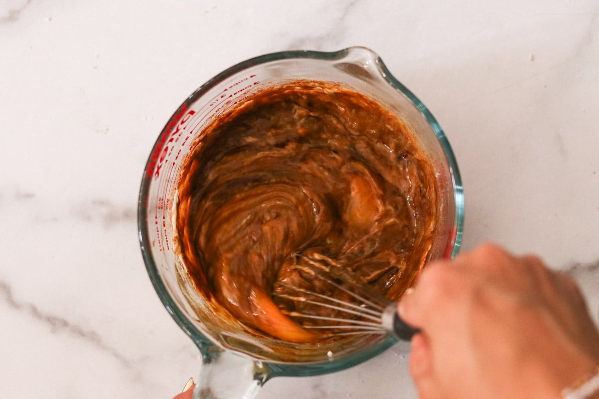 Yogurt, egg, molasses, and vanilla being whisked in a glass measuring cup.