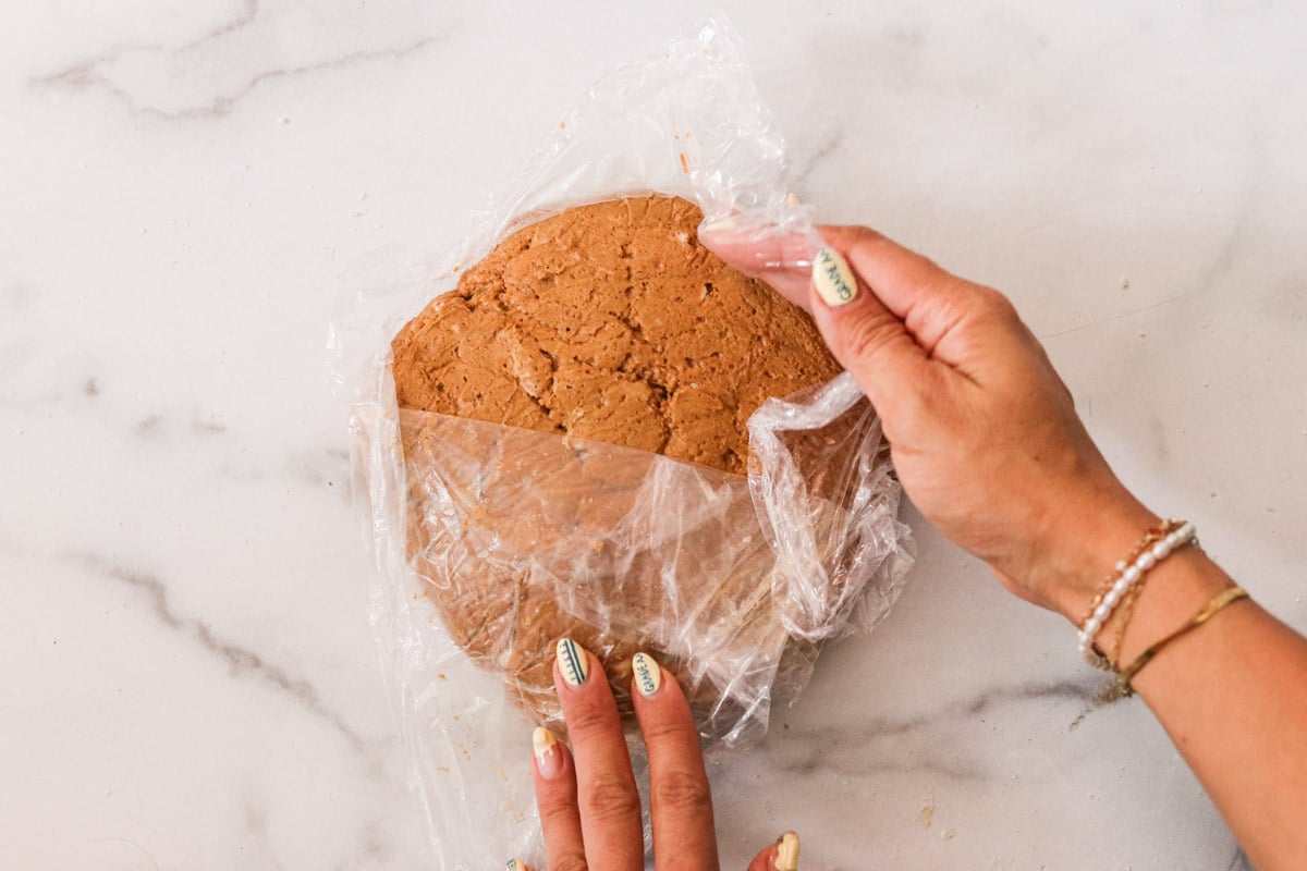 Gingerbread scone dough shaped into a 6-inch round and wrapped in plastic.