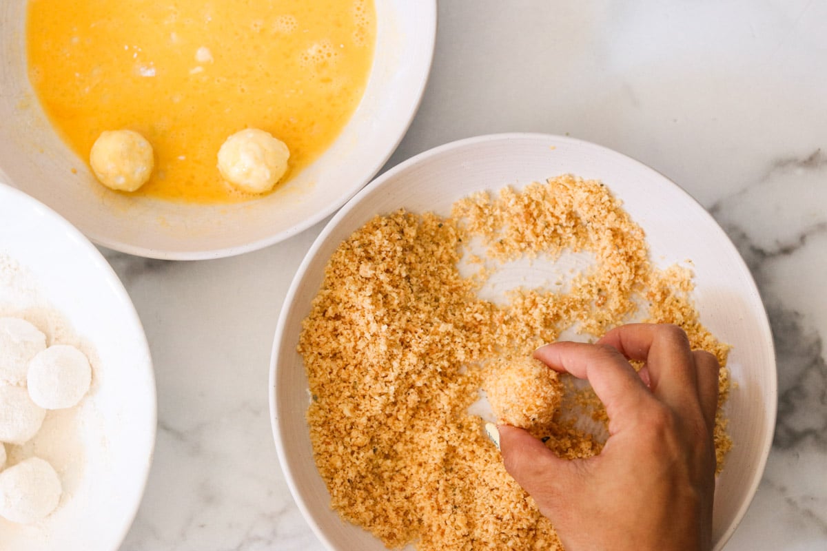 Hand rolling a flour and egg coated goat cheese ball into seasoned panko.