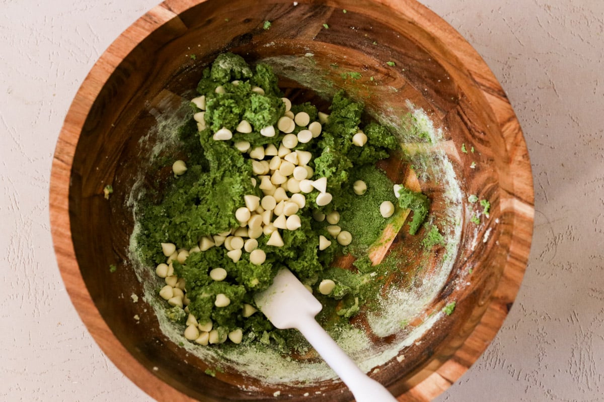 Dry ingredients added to the wet ingredients; white chocolate are being folded in with a spatula.
