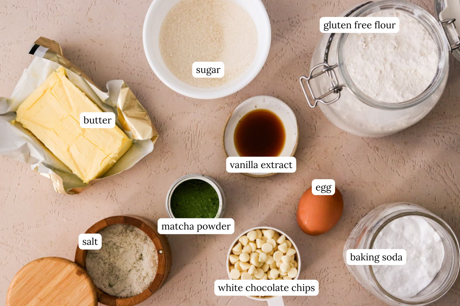 Ingredients for matcha chocolate chip cookies labeled and laid out on a light colored countertop.