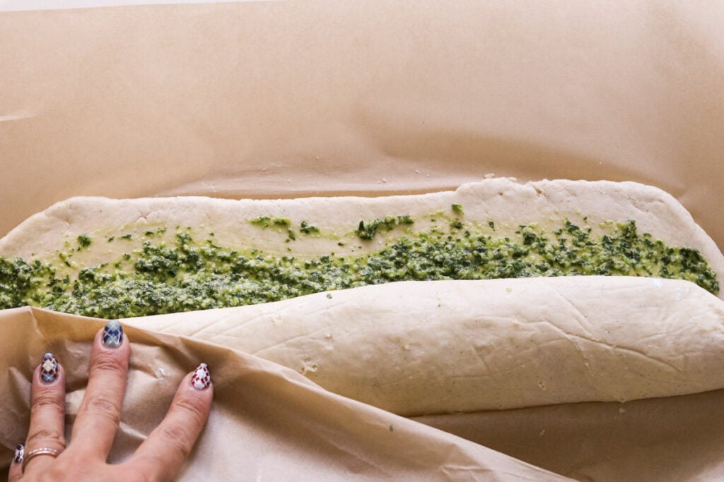 a hand rolling the dough into a long roll