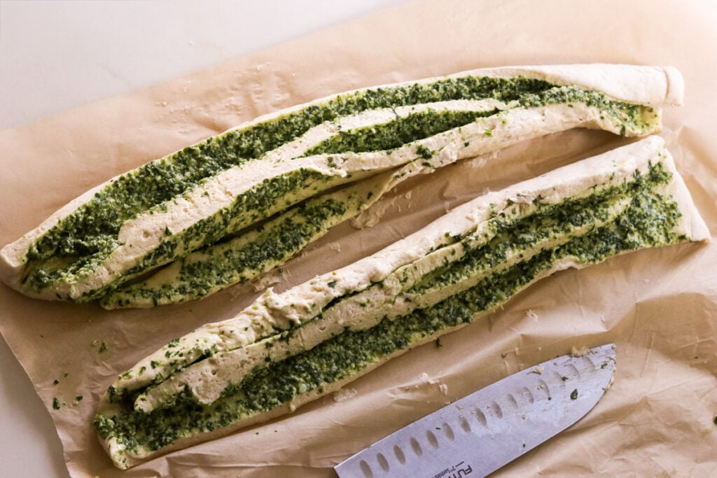 a large knife slicing through the dough roll to make two pieces