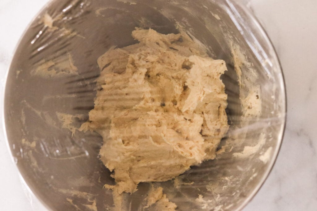 covering the mixing bowl with plastic wrap for the first rise