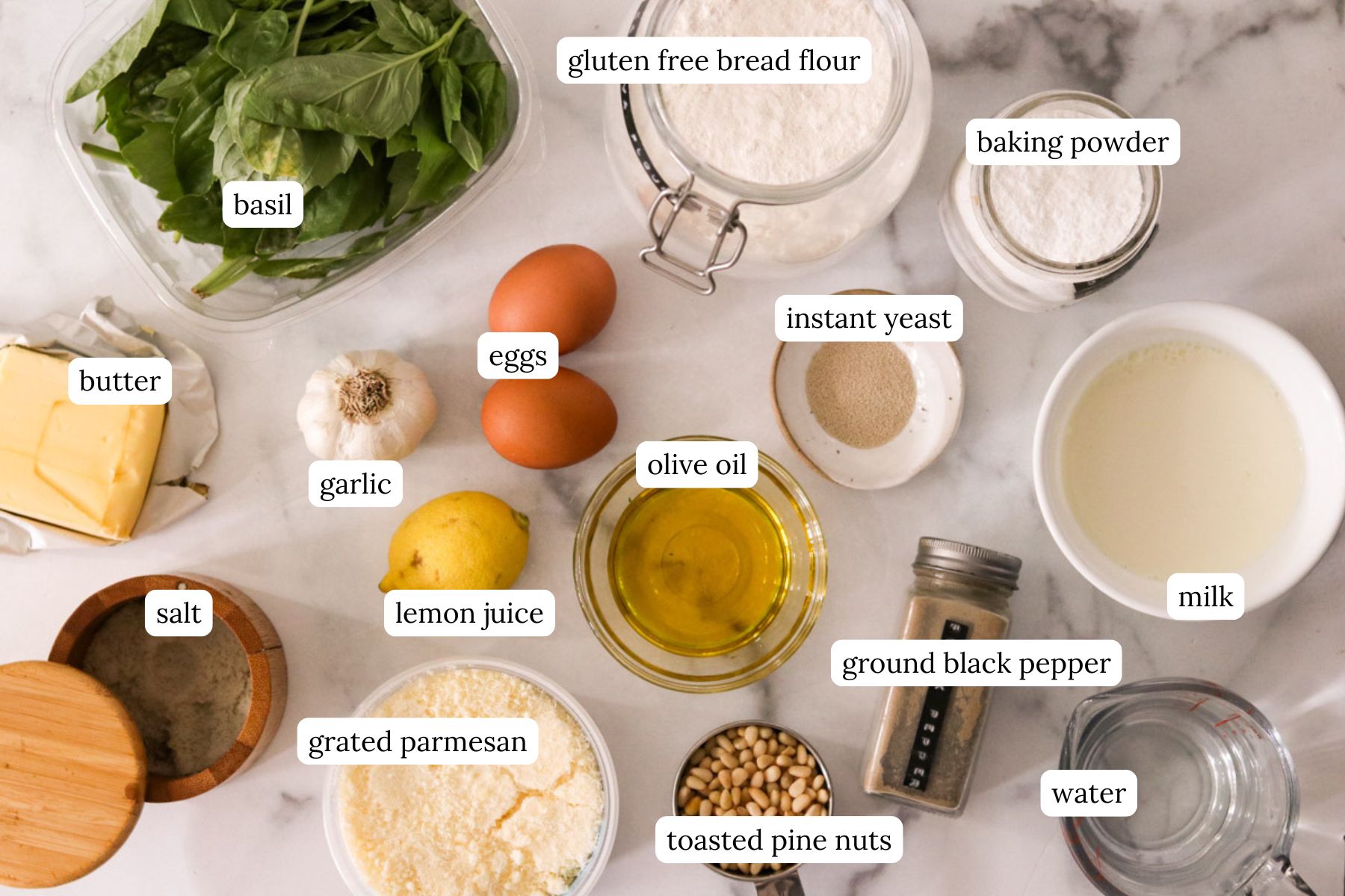 recipe ingredients for homemade pesto and wreath bread on a marble counter