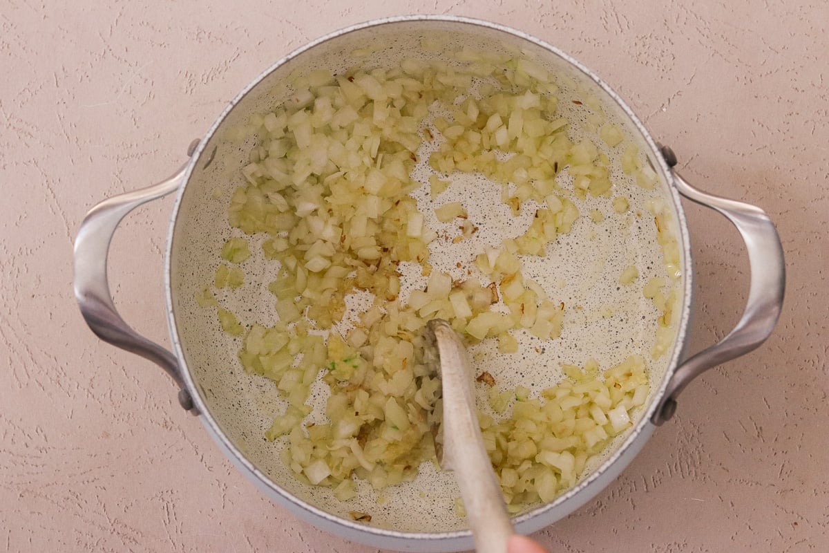 A large pot with olive oil, chopped onion, and garlic.