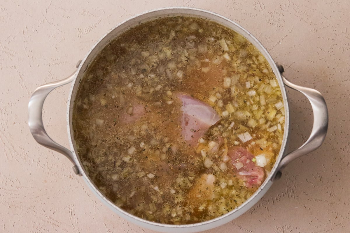 Chicken, Italian seasoning, sea salt, and chicken broth added to the pot with sautéed onion and garlic.