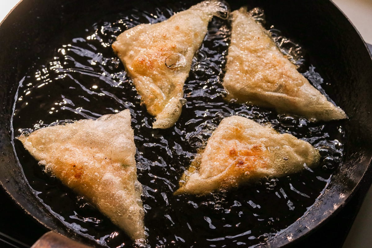 Gluten-free crab rangoons frying in a pan.