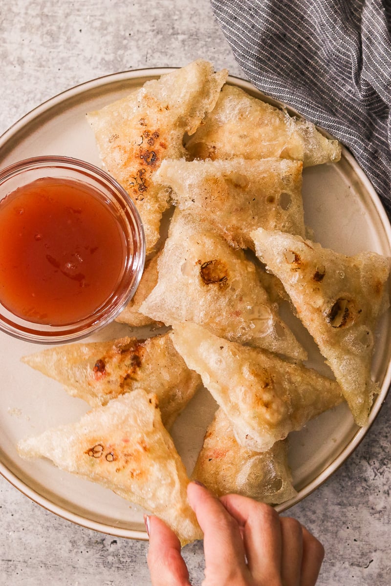 Gluten-free crab rangoon served on a plate with a small bowl of sweet and sour sauce.