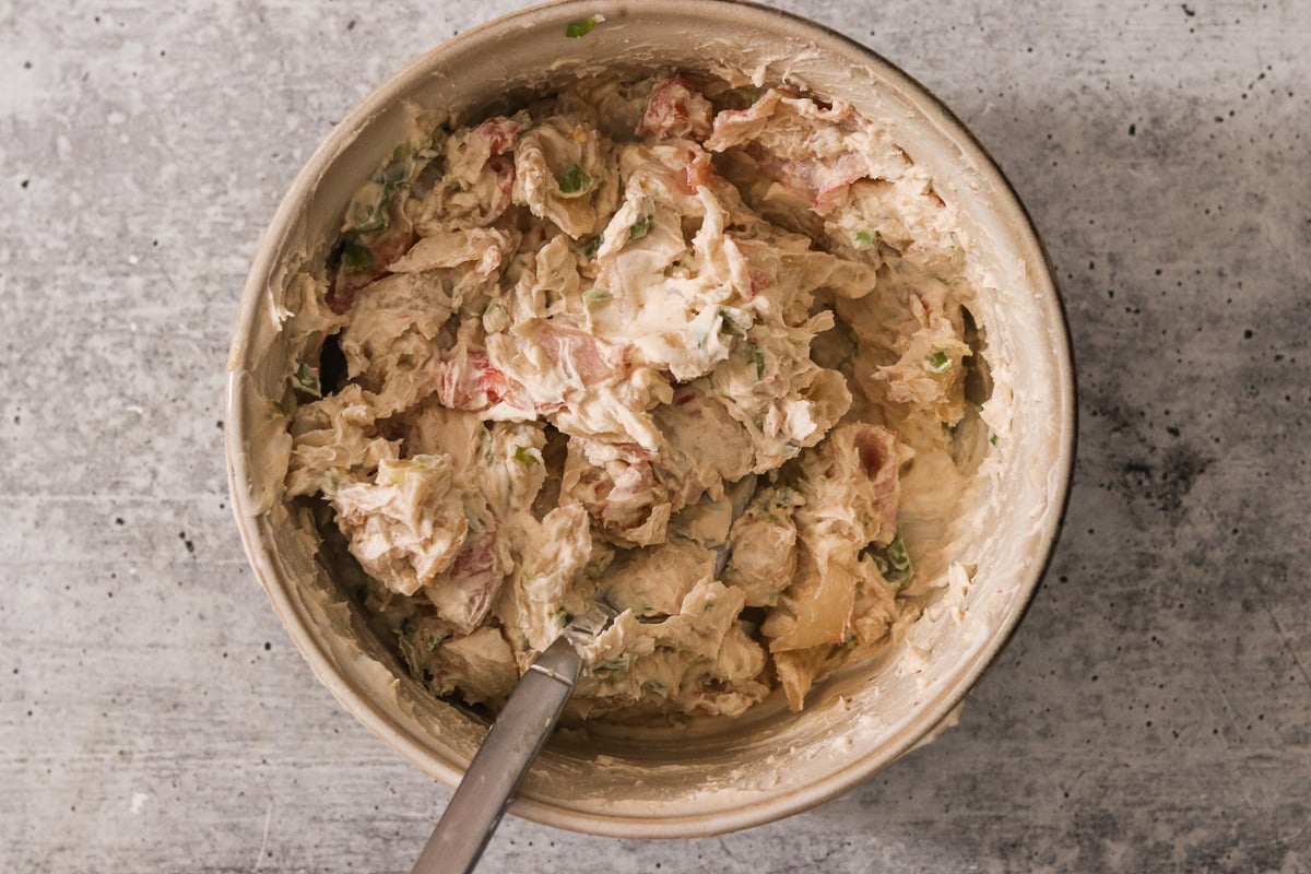 A medium bowl with crab meat, cream cheese, green onion, tamari sauce, Worcestershire sauce, garlic powder, and sugar.