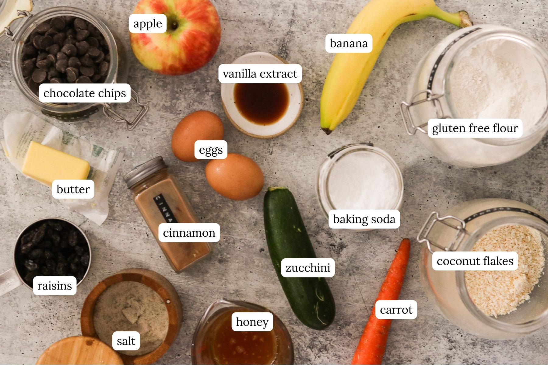 Gluten-free morning glory muffins recipe ingredients labeled and laid out on a gray countertop.