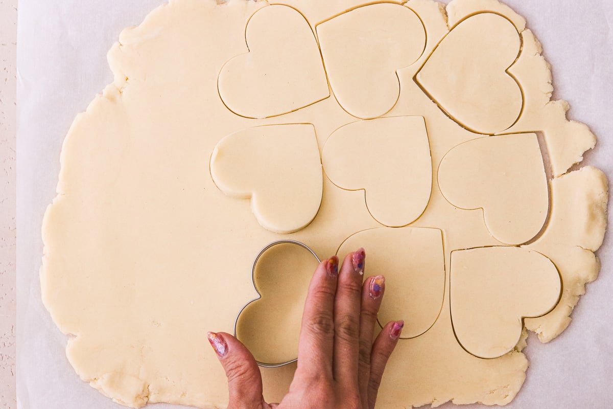 Heart shapes being cut from chilled gluten-free dough.