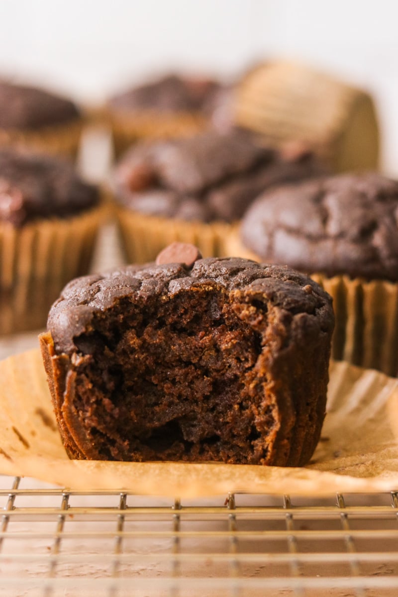Close-up of a hidden veggie chocolate muffin with the liner peeled back and a bite taken out.