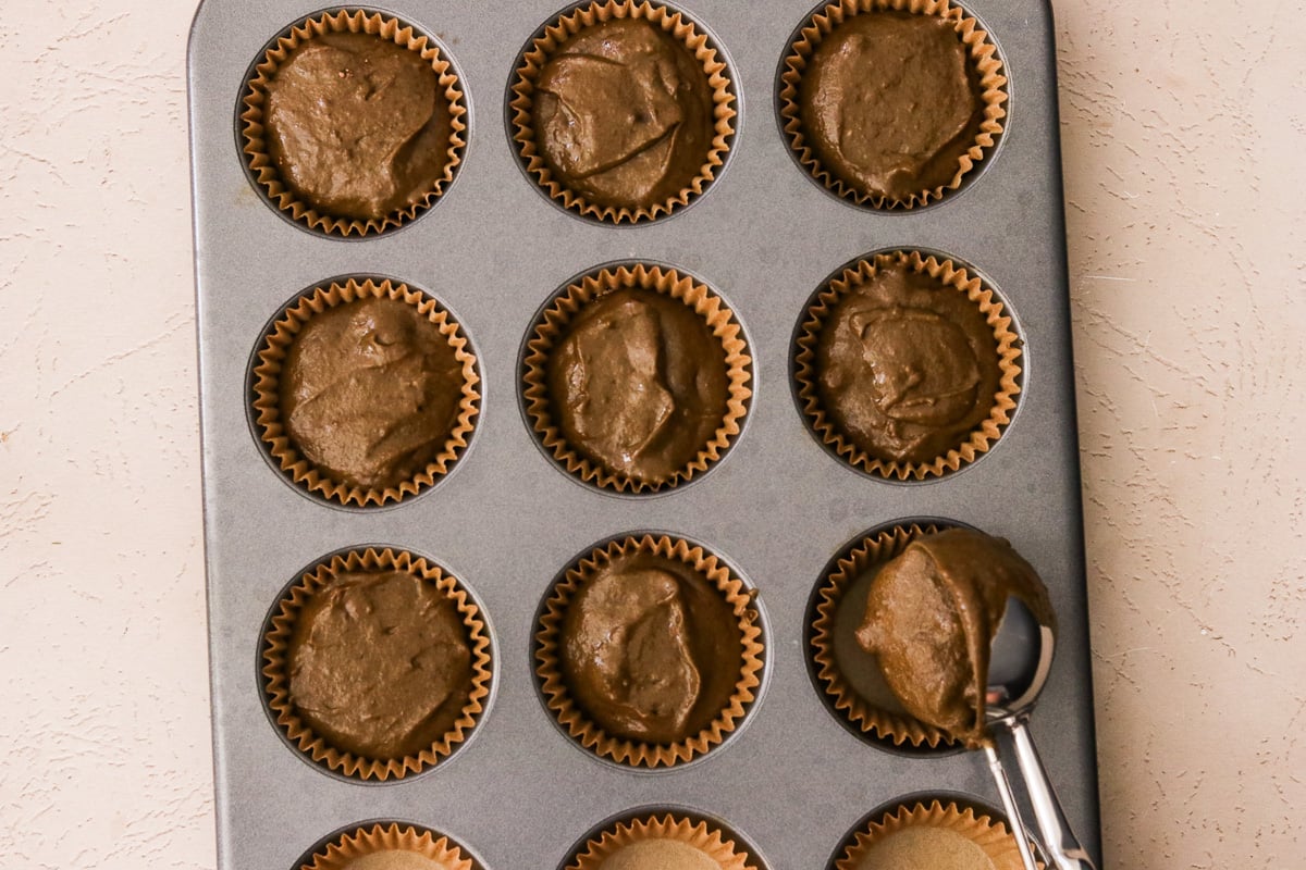 Hidden veggie chocolate muffin batter divided evenly into a lined muffin tin with extra chocolate chips on top.