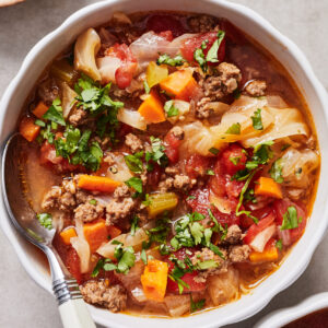 Instant pot cabbage soup in a white bowl with a spoon resting on the side.