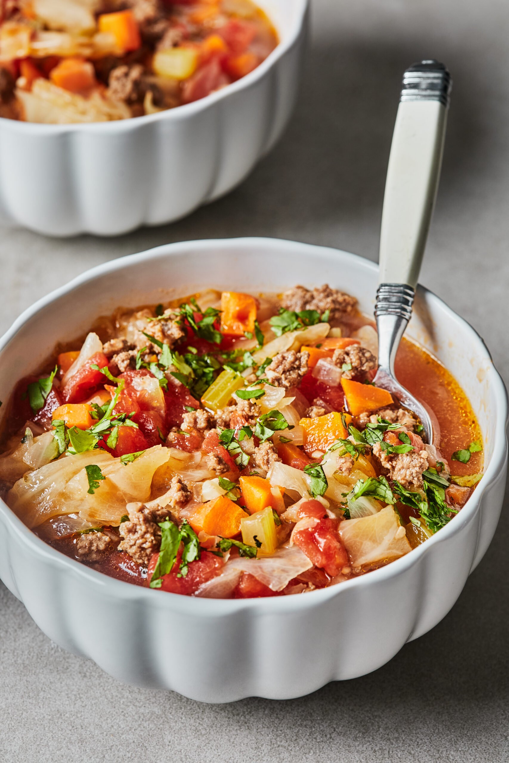 a bowl of instant pot cabbage soup with a spoon resting on the side