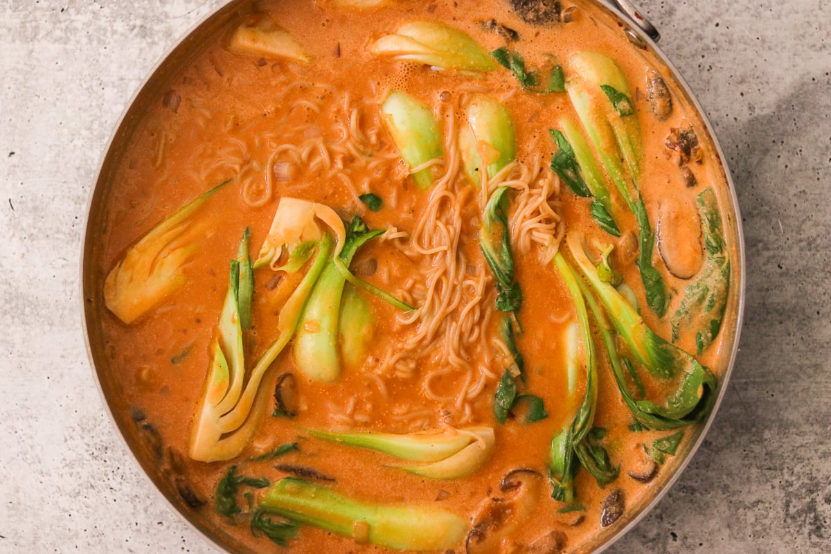 Baby bok choy and cooked chicken added to coconut curry ramen.
