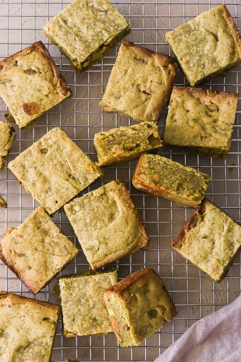 Sliced pistachio blondies on a wire cooling rack.