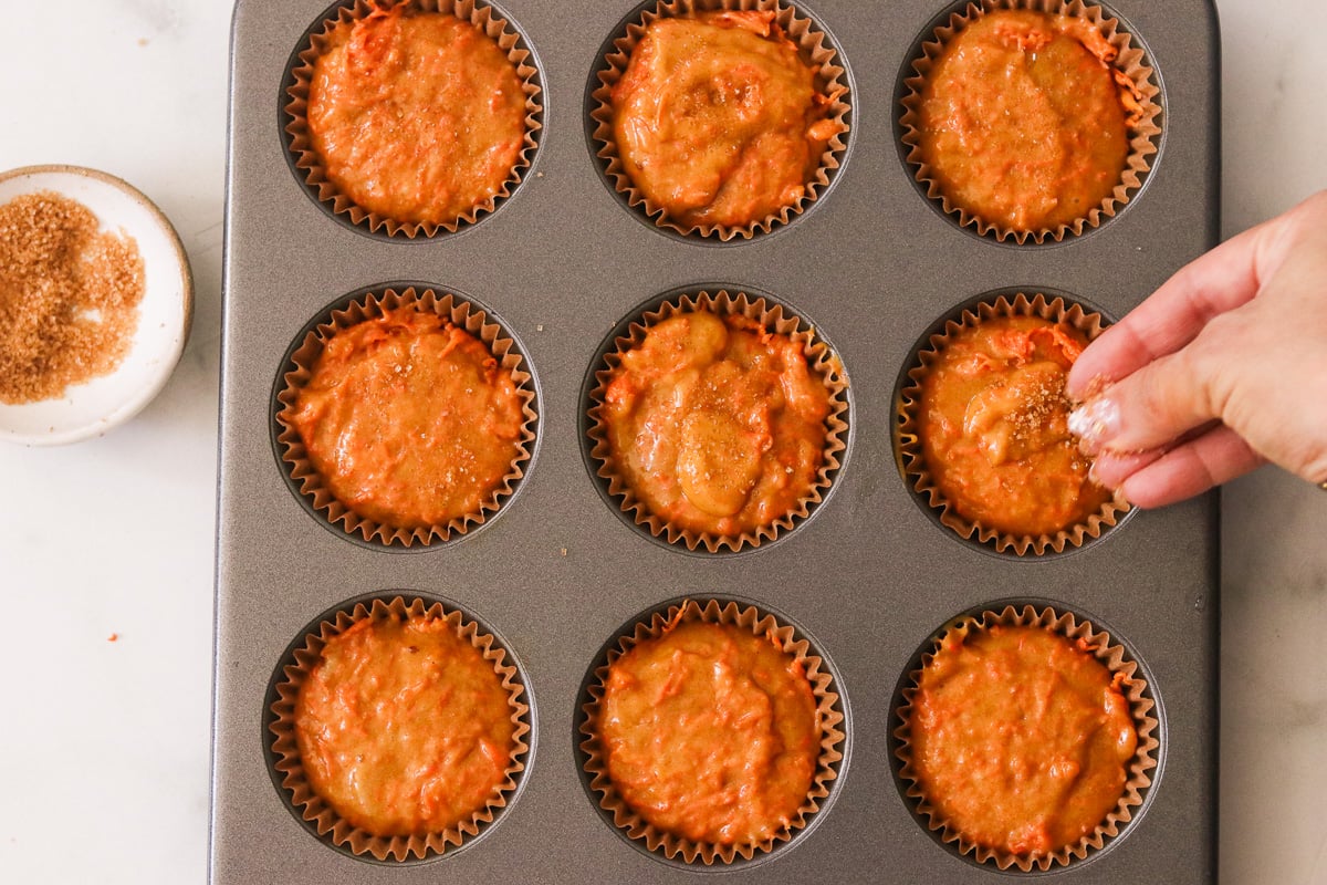 Muffin cups topped with more batter and sprinkled with turbinado sugar before baking.
