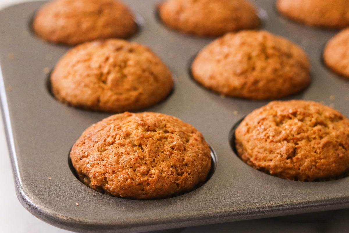 Freshly baked gluten-free carrot cake muffins cooling in a muffin tin straight from the oven.