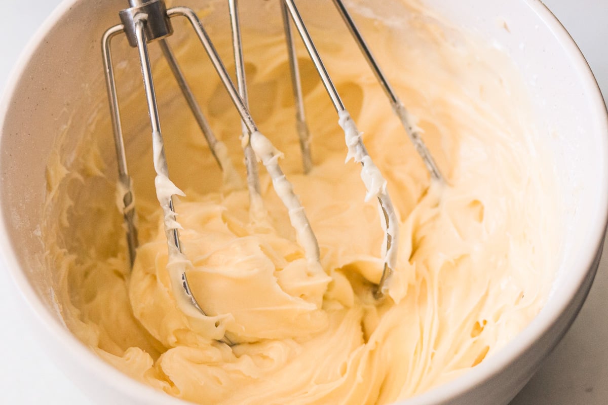 Electric mixer mixing cream cheese, sugar, and vanilla in a small bowl until smooth and creamy.