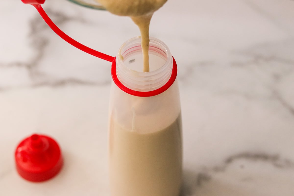 Pouring funnel cake batter into a squeeze bottle for frying.