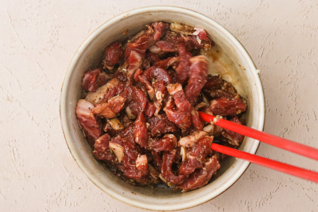 ribeye steak marinating in a bowl