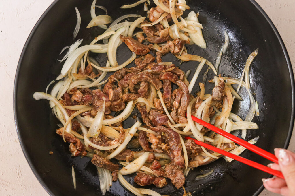 sauteeing beef and onions in a skillet