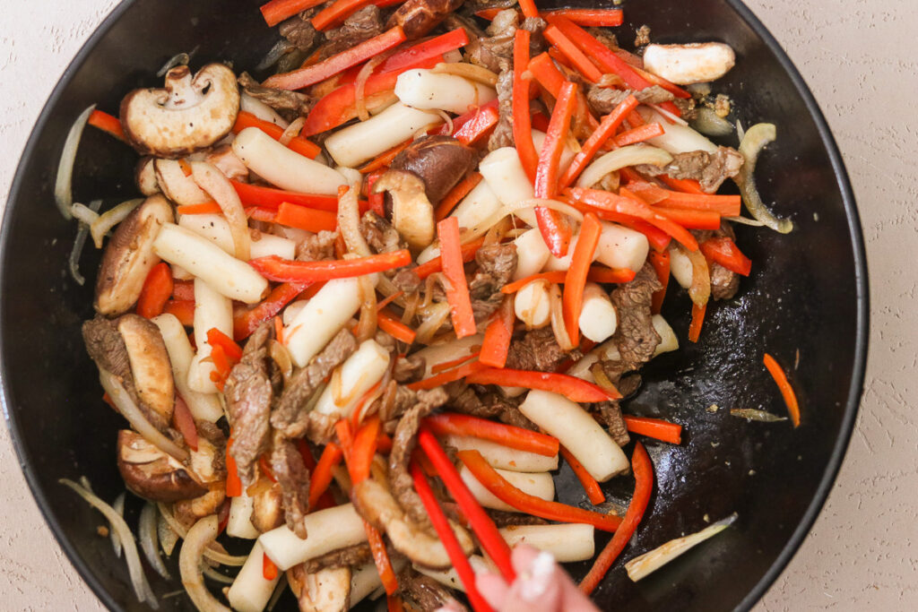 sauteeing veggies alongside the beef and onions in a skillet