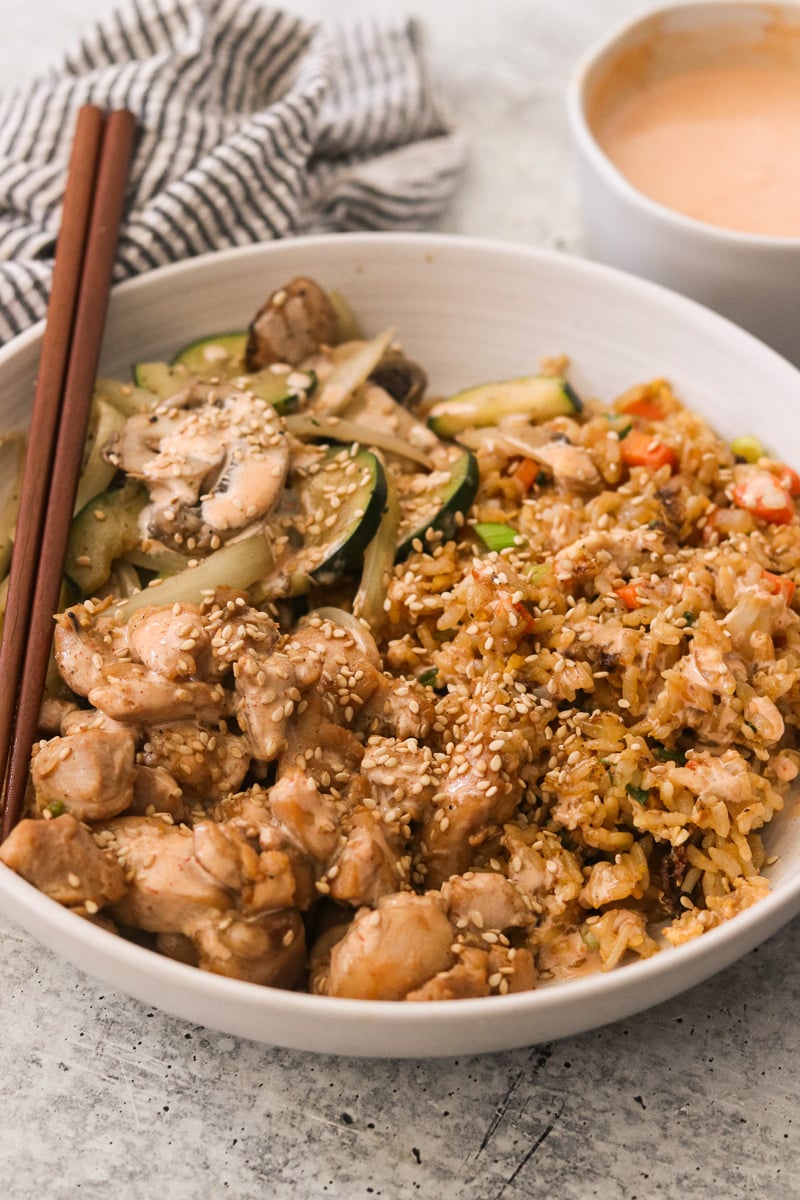 Close-up of hibachi chicken bowls garnished with sesame seeds with chopsticks lying in the bowl.