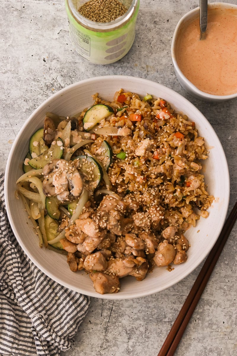 Hibachi chicken bowl garnished with sesame seeds and yum yum sauce.