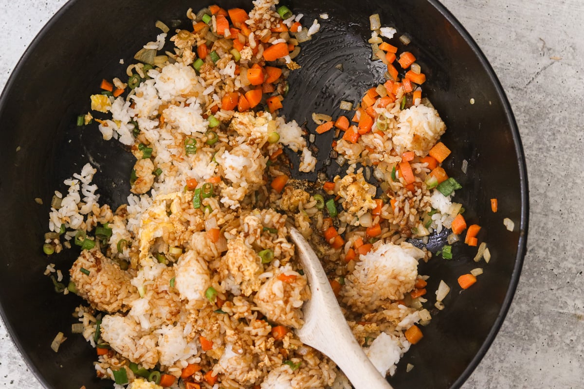 Cold rice, green onions, and hibachi sauce stirred into the skillet with the eggs and vegetables.