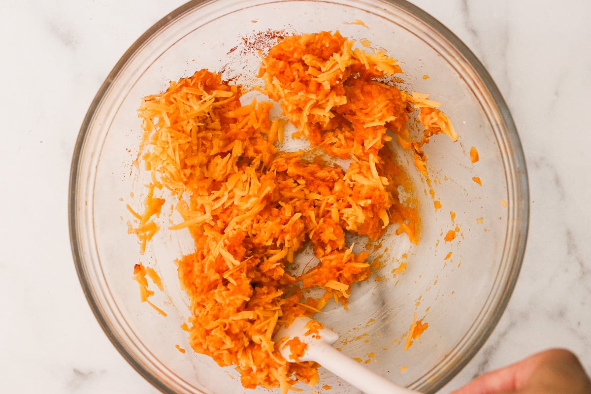 Mixing sweet potato puree, shredded cheddar cheese, butter, and spices in a large bowl until well combined.