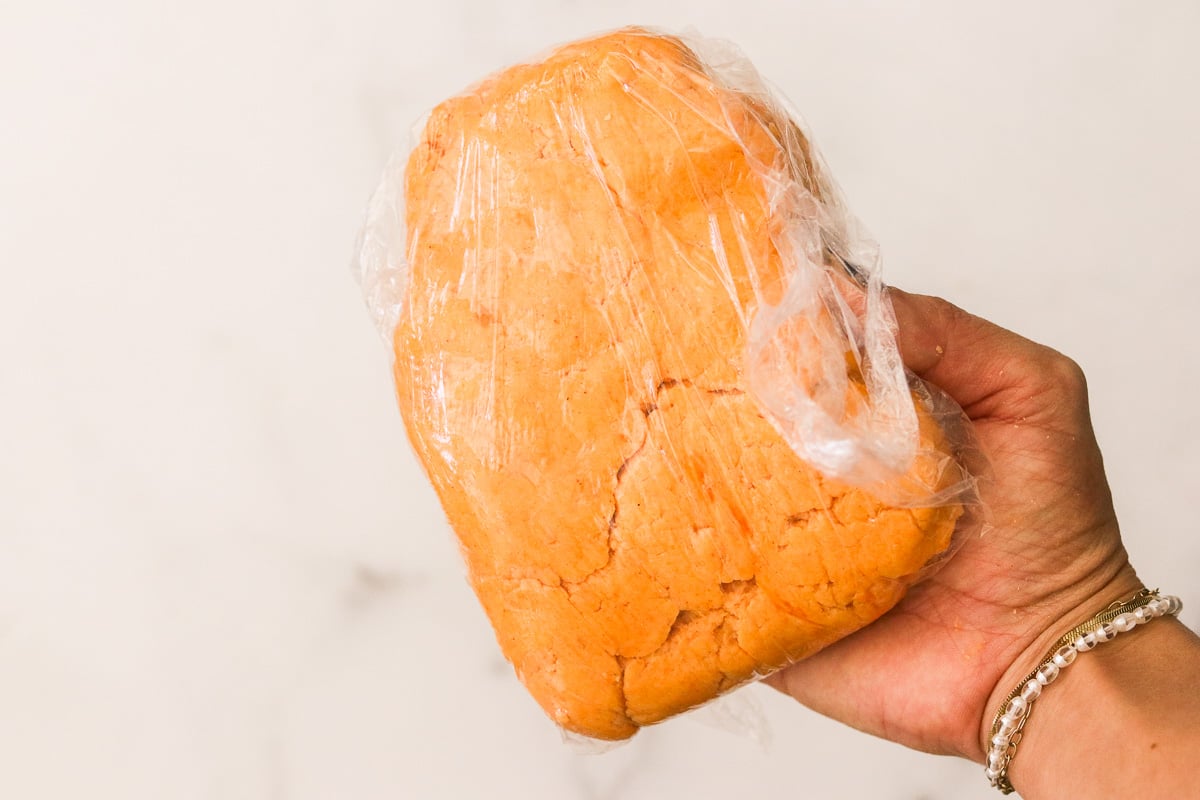 Sweet potato cracker dough wrapped in plastic wrap ready to chill.
