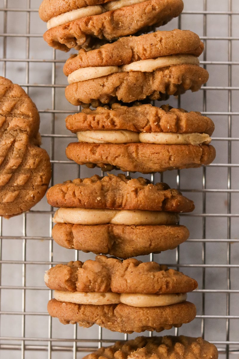 Close-up of gluten-free nutter butters turned on their sides to show the creamy peanut butter filling cooling on a wire rack.