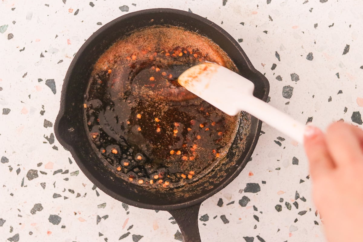 Butter melting with red pepper flakes and smoked paprika in a saucepan.