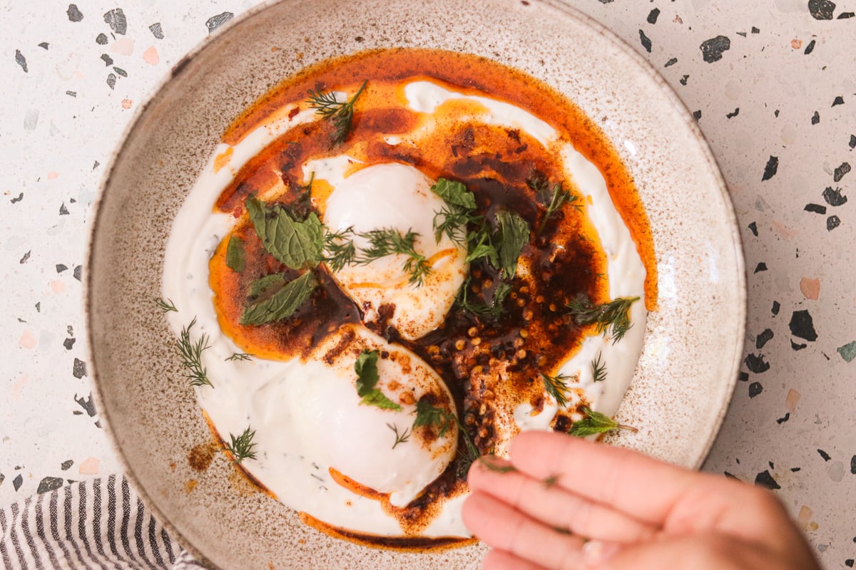 Turkish eggs assembled with yogurt, poached eggs, and chili butter with mint.