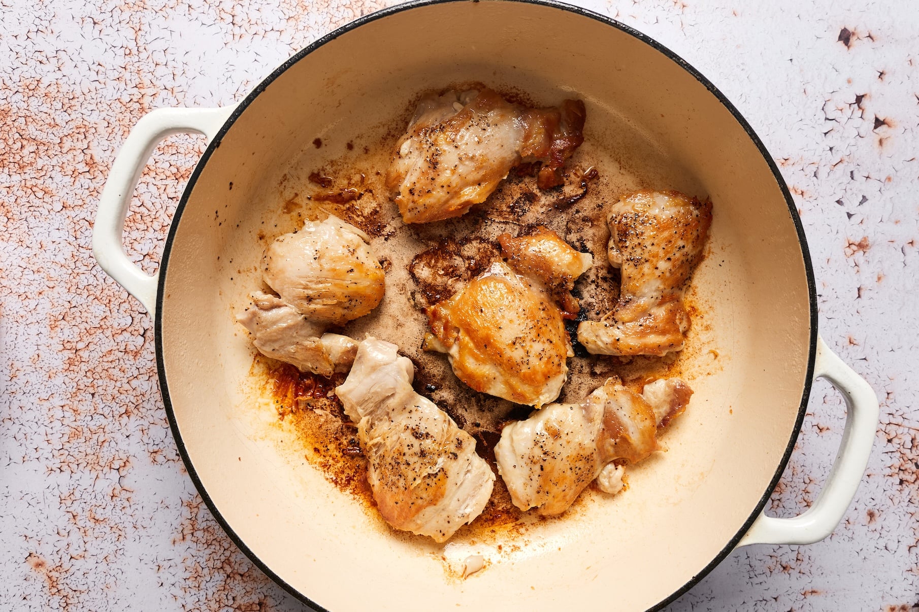 Seasoned chicken cooking in a hot skillet in a single layer until golden brown on the bottom.