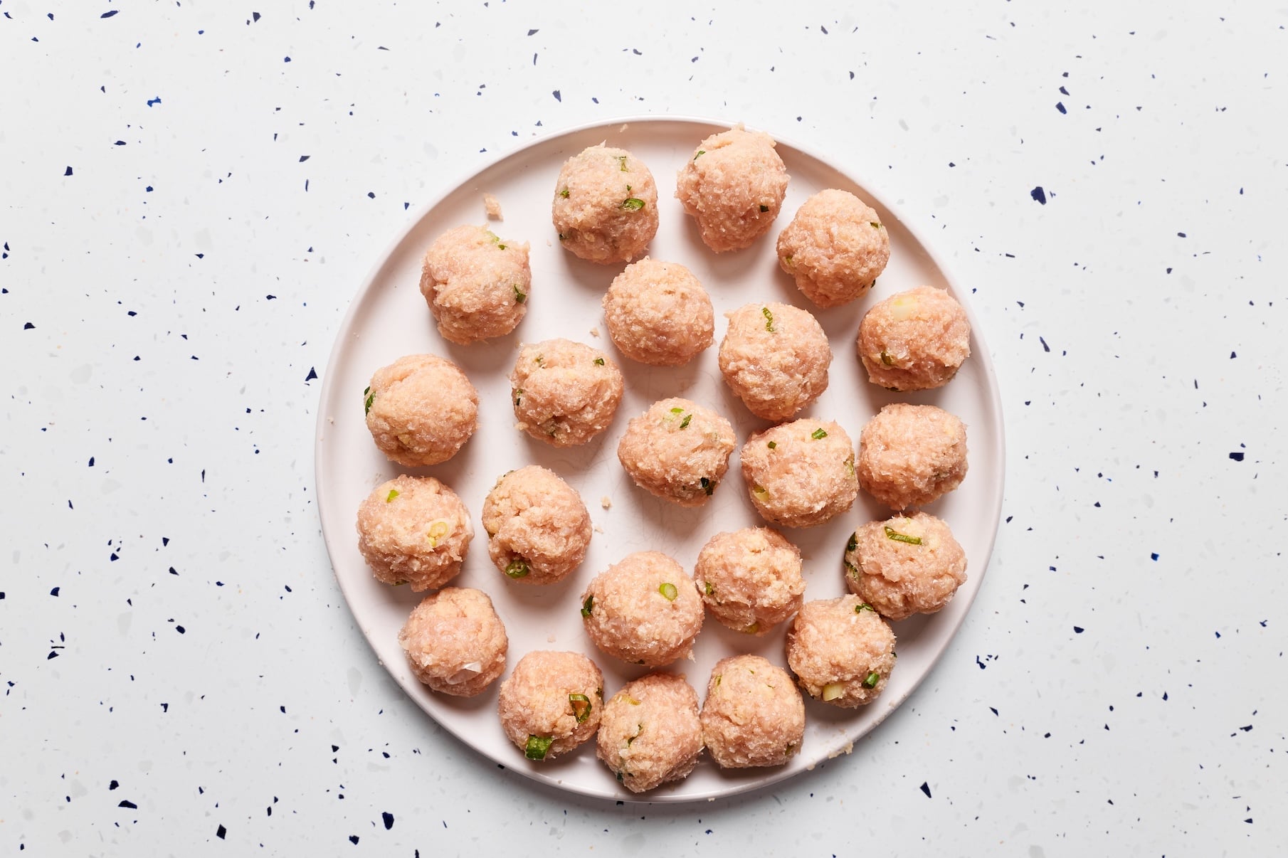 Raw buffalo chicken meatballs shaped into golf ball-sized portions and arranged on a plate before cooking.