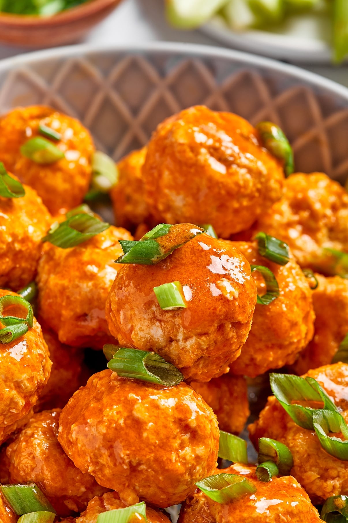 Close-up of buffalo chicken meatballs garnished with chopped green onions.