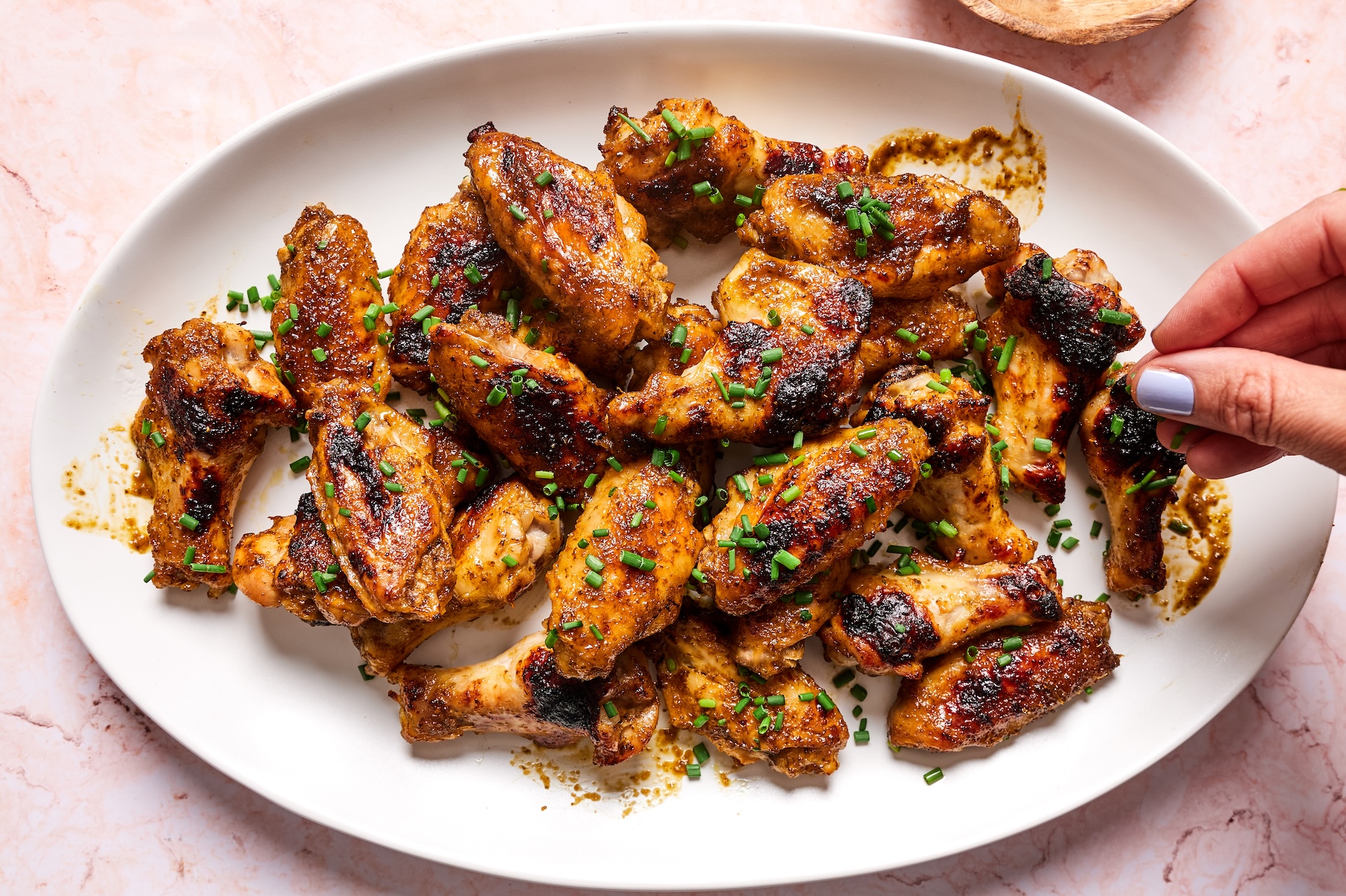Paleo chicken wings on a serving platter garnished with freshly chopped chives.