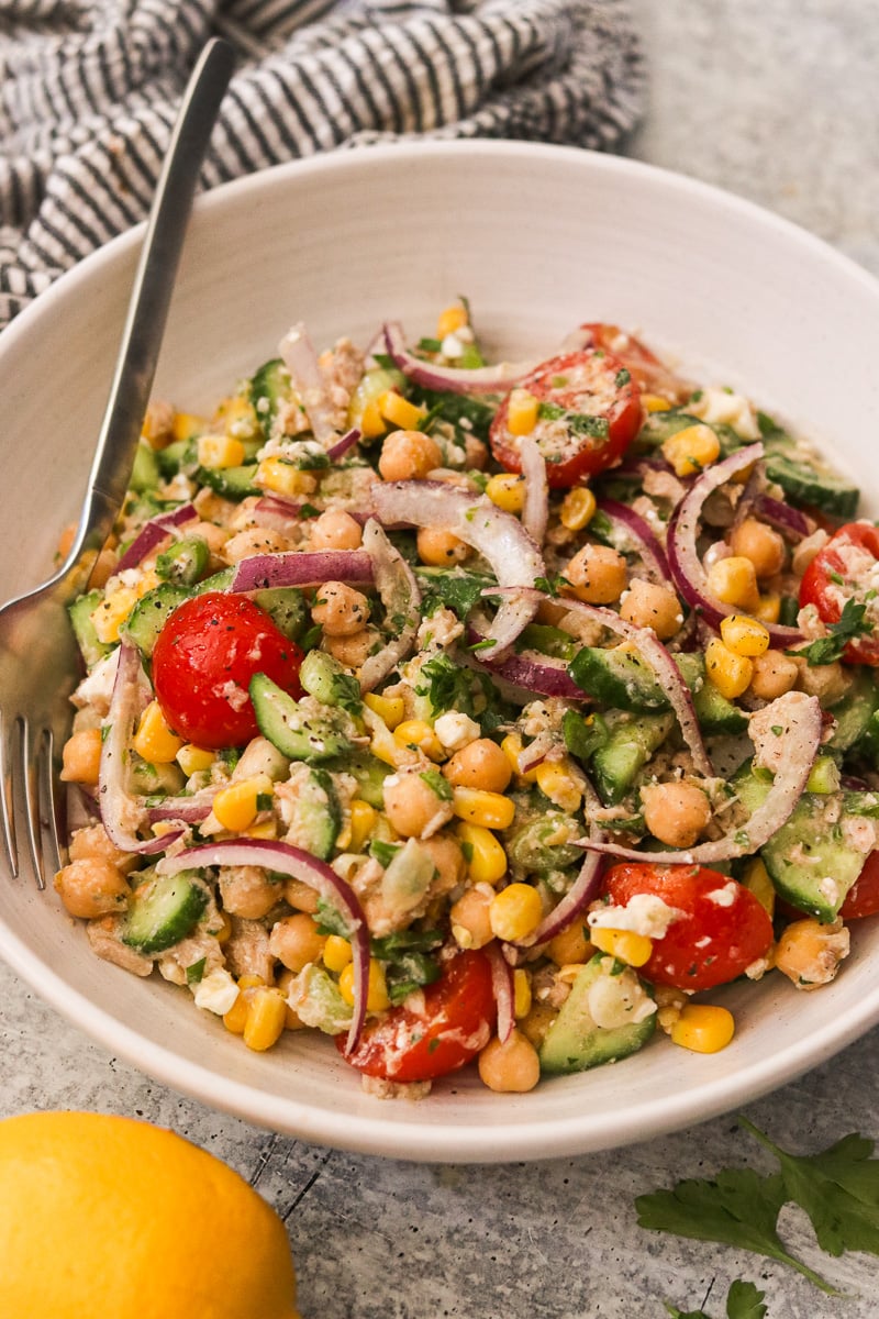 Close up of high protein chickpea tuna salad with crunchy vegetables and a fork in the bowl.