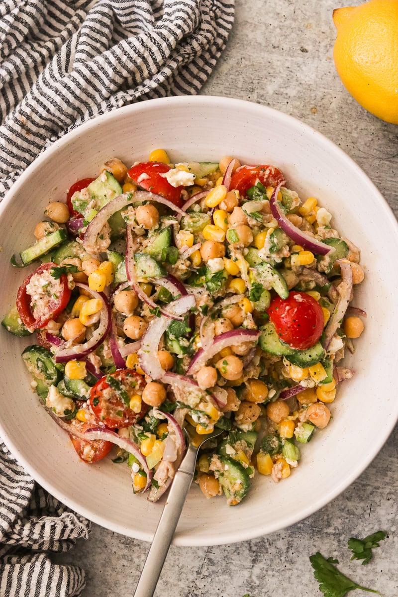 High protein chickpea tuna salad in a bowl with a fork and striped linen towel on the side.