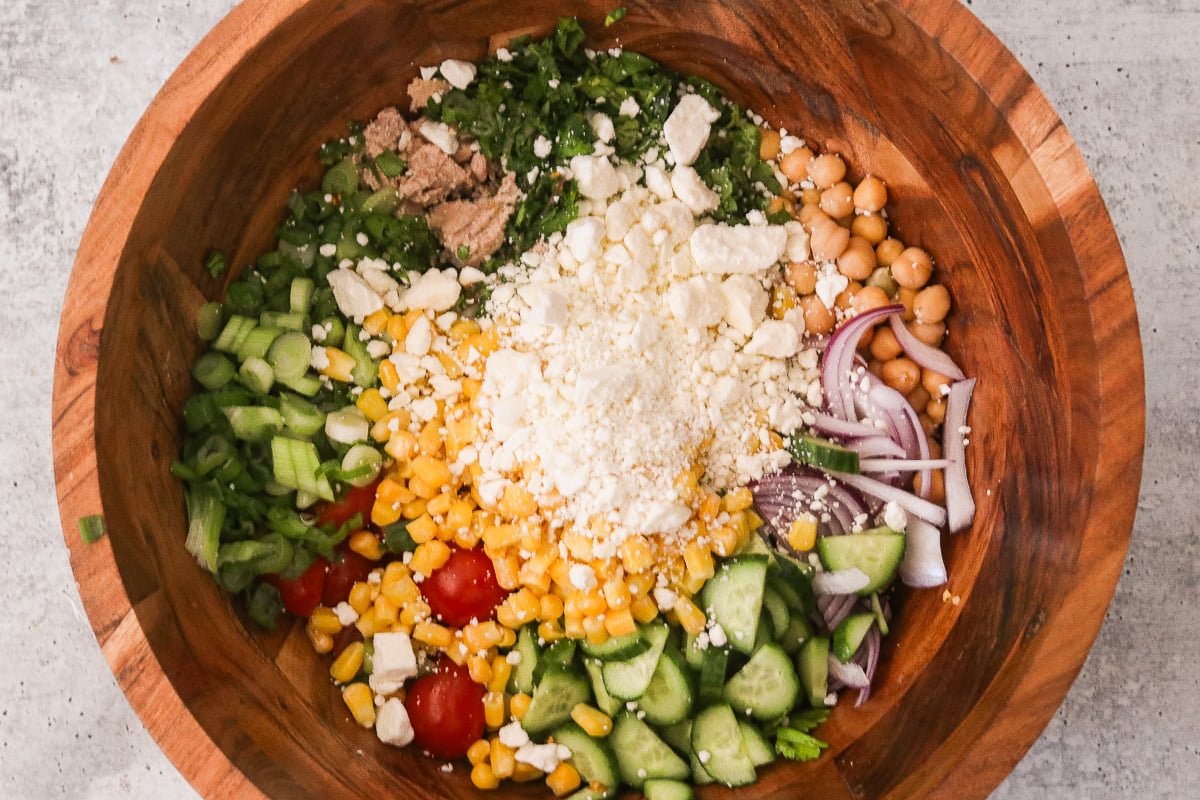 Ingredients for chickpea tuna salad in a wooden mixing bowl before tossing.