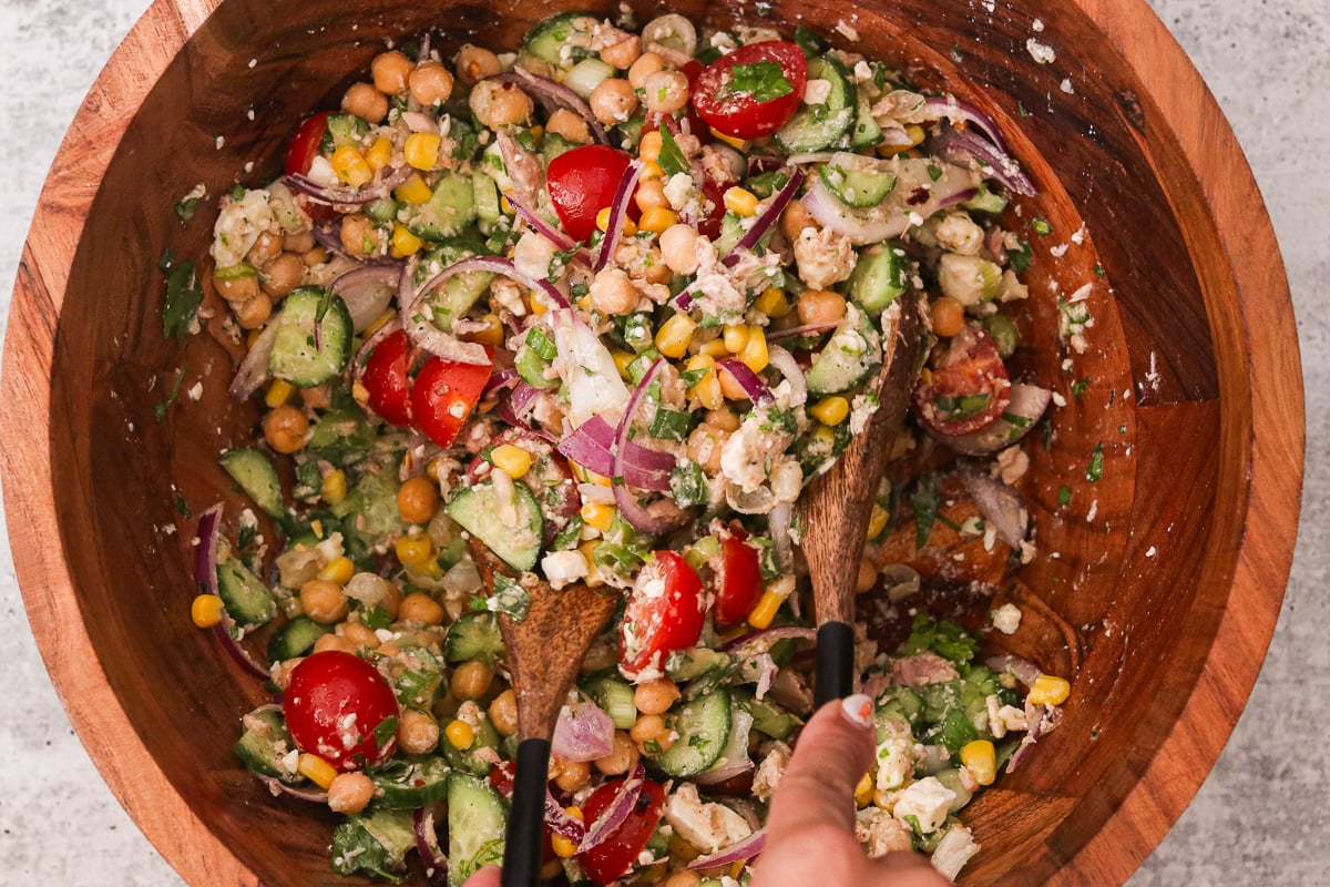 Finished high protein chickpea tuna salad being tossed with serving spoons.